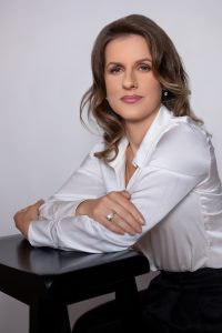 Woman with dark hair in white blouse with hands folded on table. Modern headshots for women by Laquel Wright Photography headshot photographer in Lawrenceville GA